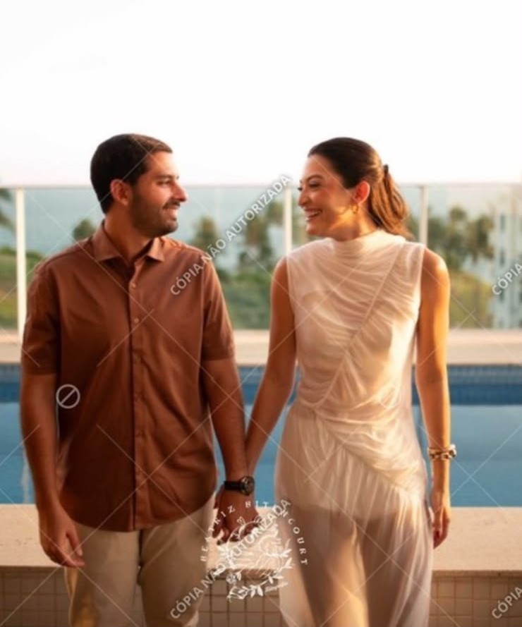 Júlia e Caio de mãos dadas à beira da piscina